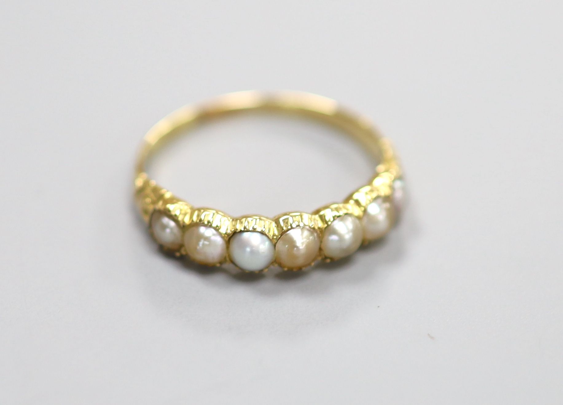 A late Victorian yellow metal and split pearl set half hoop ring